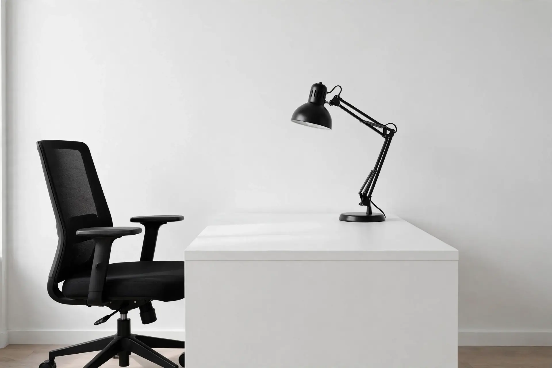 White desk with black chair and black lamp creating monochrome contrast